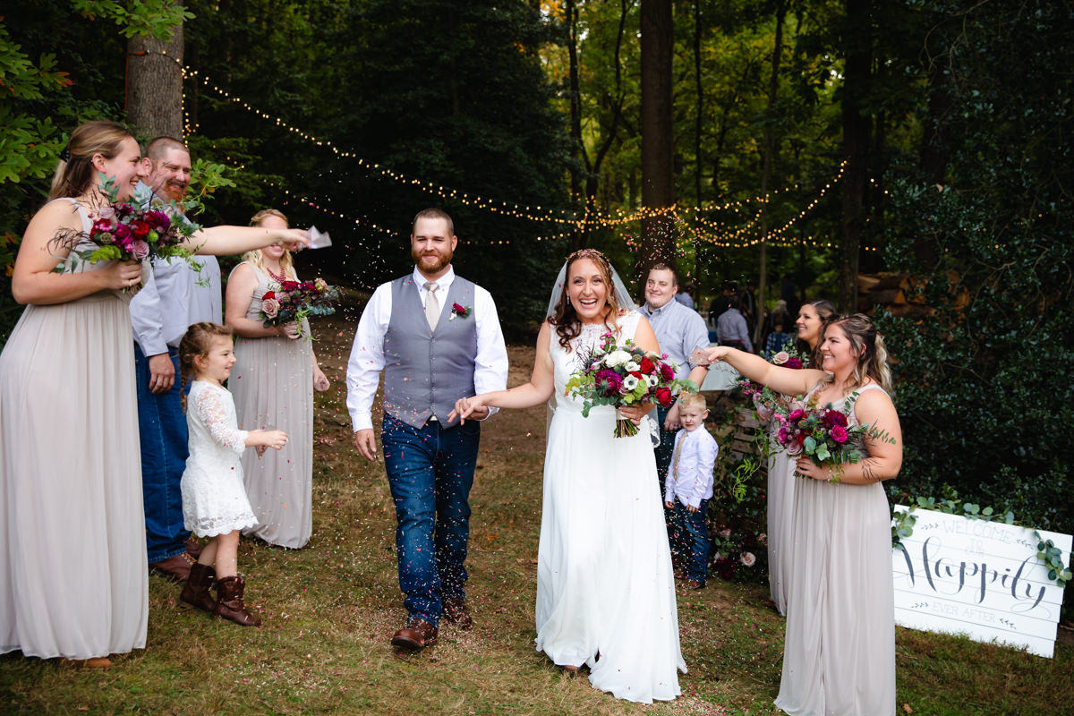 Happy couple having the time of their lives during their grand exit as a married couple, wedding party showering them with flower petals