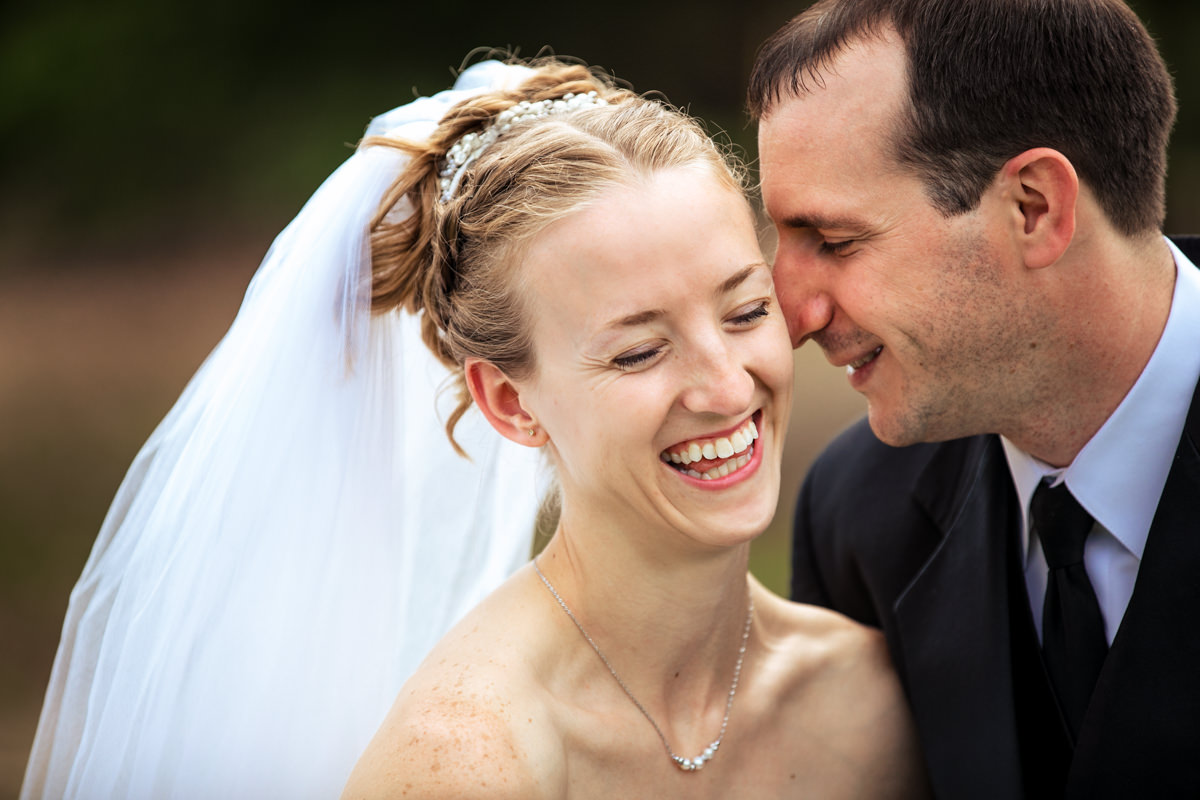 Groom nuzzling his nose into the brides cheek while she laughs