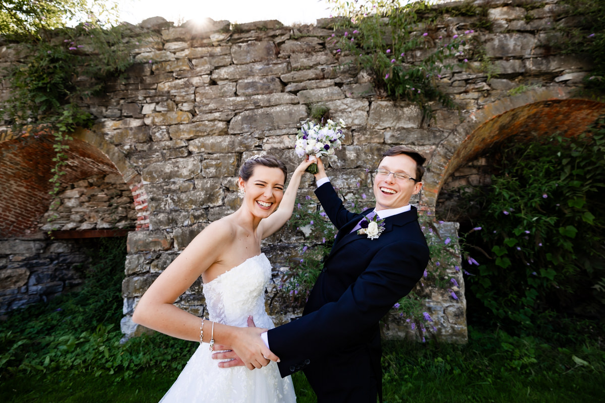 Couple having fun dancing during portraits by stone wall