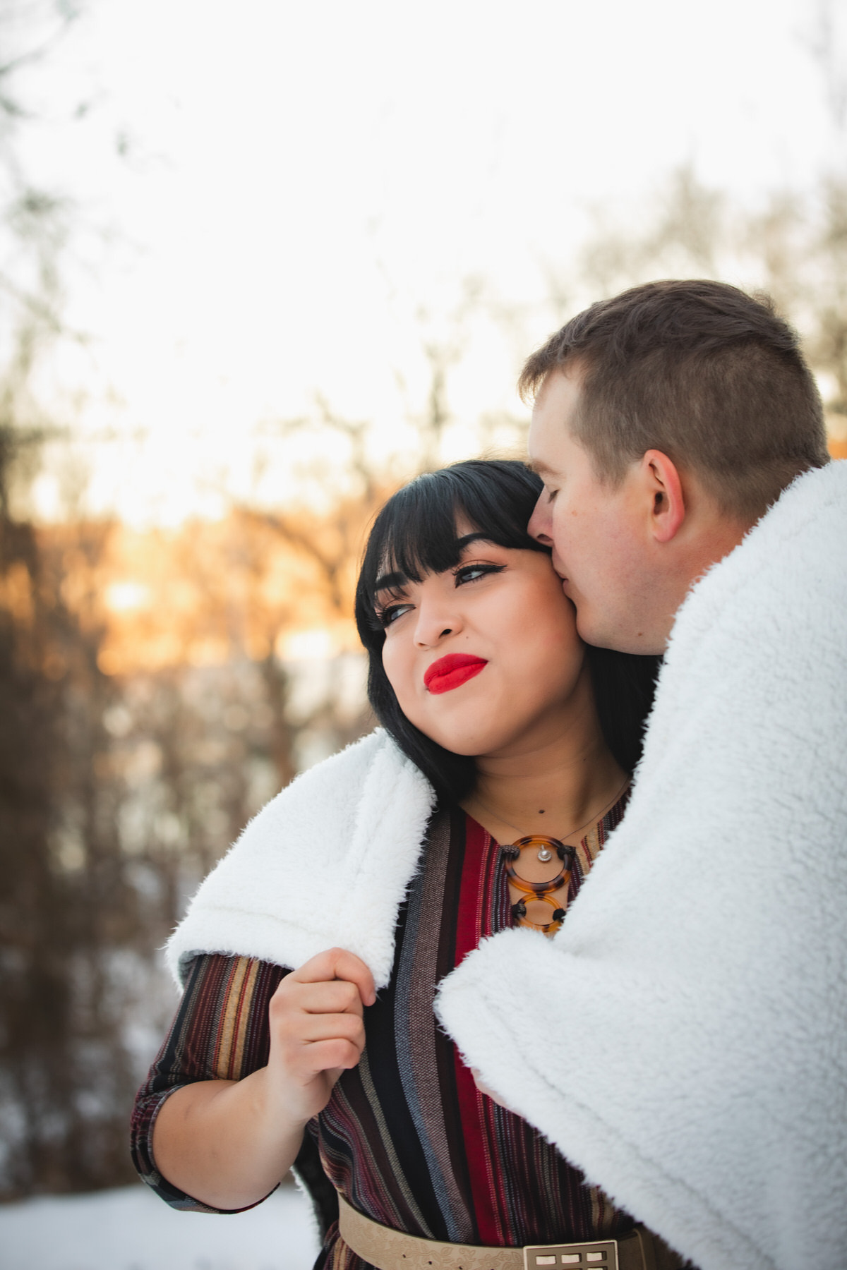 Man kisses woman on cheek during snowy session