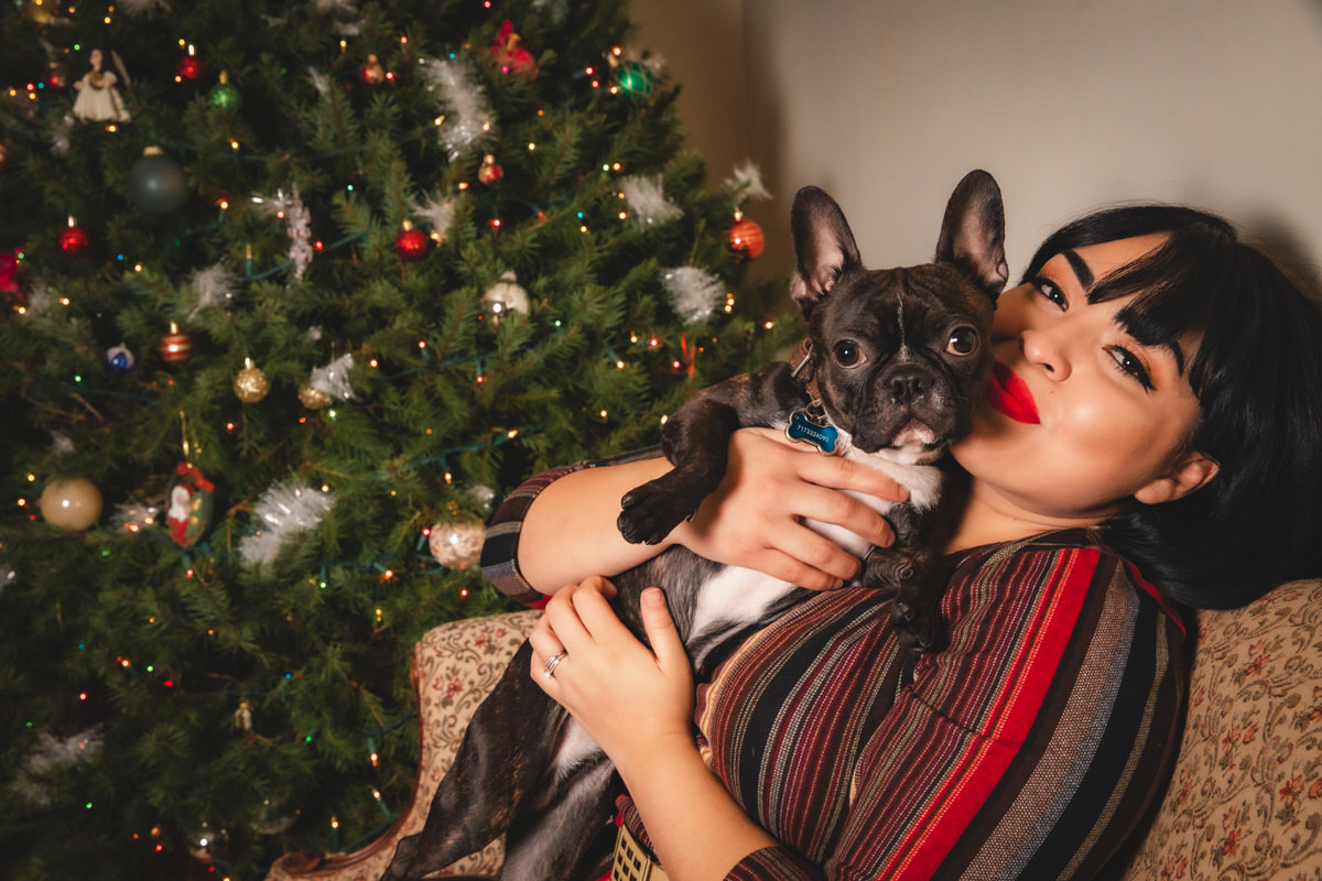 Women snuggled up with french bulldog on couch