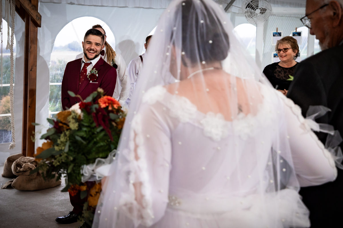 Groom excitedly smiling at first time he sees bride as she walks down the aisle