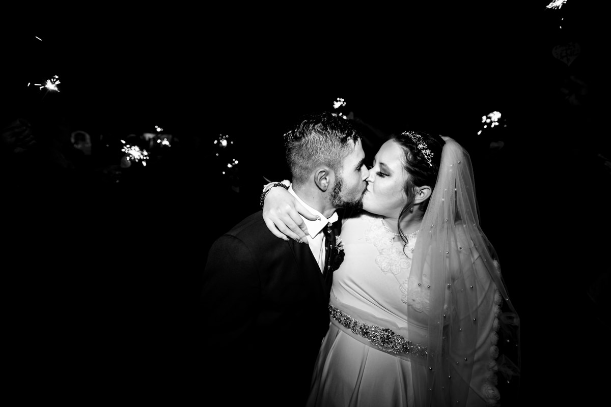 Newly married couple share a kiss durning sparkler exit