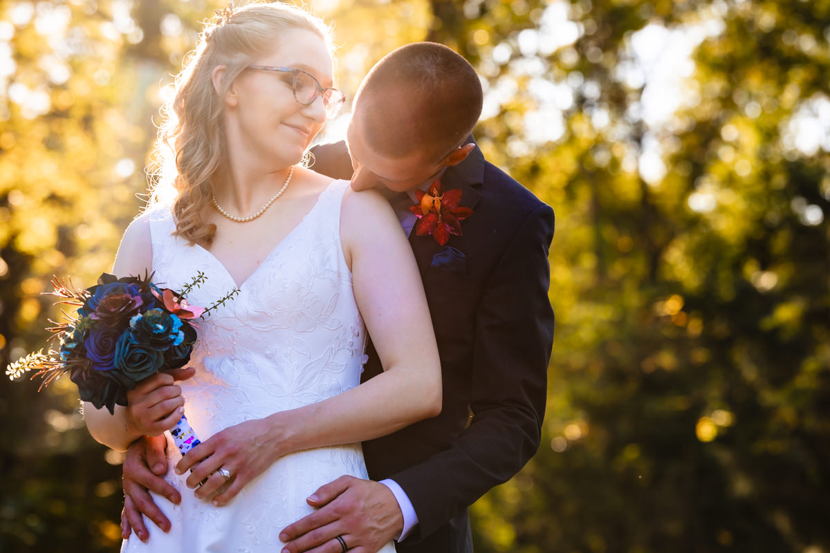 Groom behind bride kissing her shoulder. This calm moment created a better wedding photo.