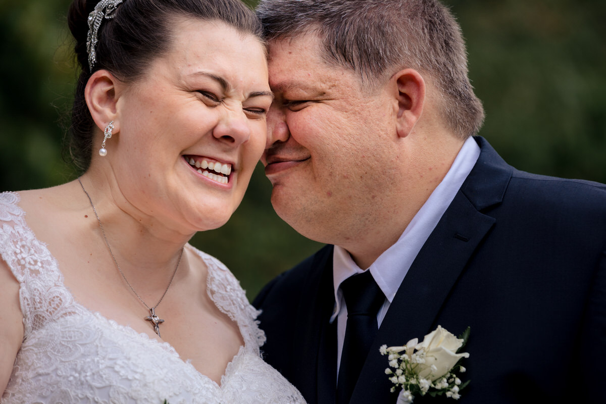 Groom making bride laugh by snuggling into her cheek