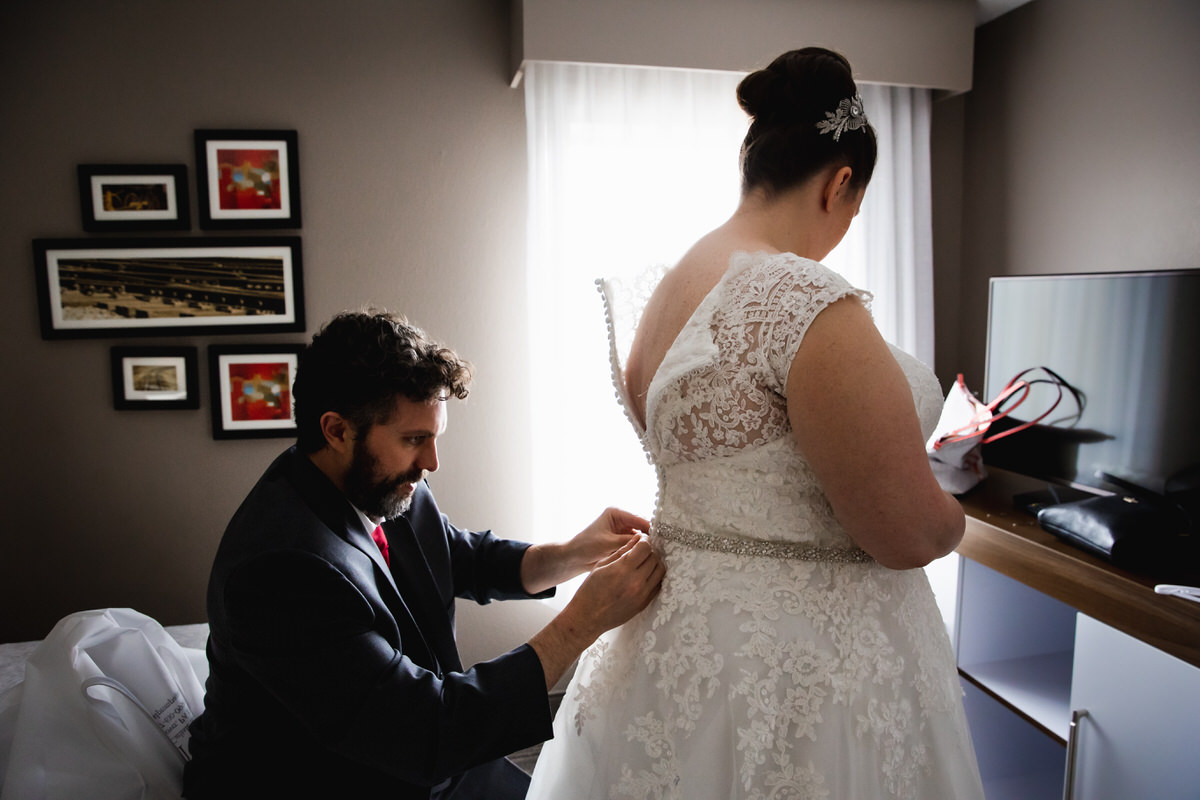 Friend helping button the brides back of dress