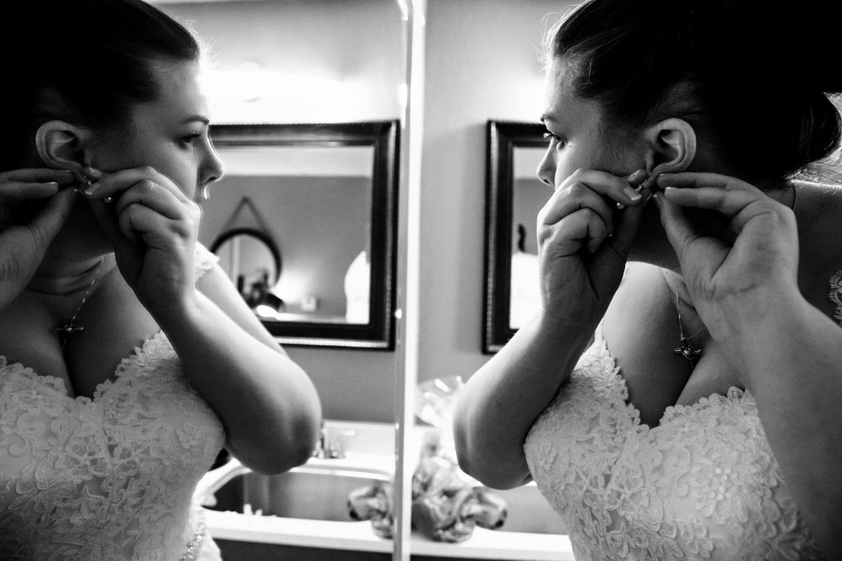 Bride putting earrings on as she gets ready at the Hampton Inn