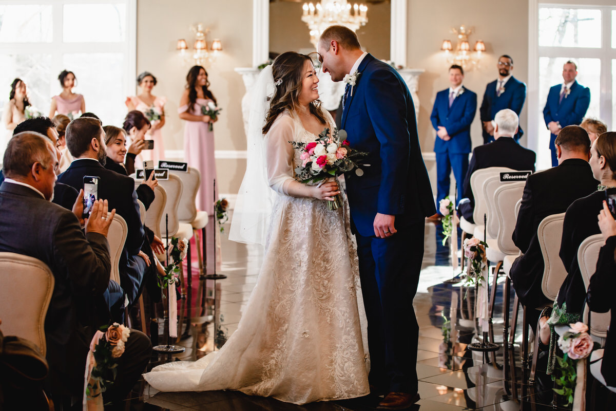 Groom leans in for a kiss as they exit their ceremony in the Conservatory