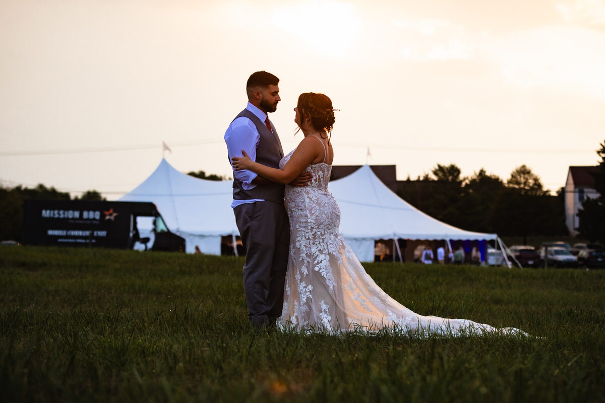 Couple enjoying a moment outside the reception tent at sunset.