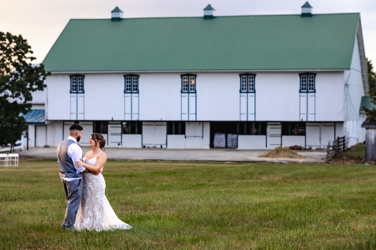 Bride and groom looking at each other with the barn in the background