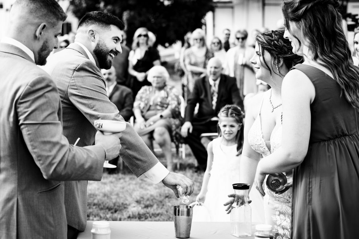 Guests watching couple mix their unity margarita during their family farm wedding.