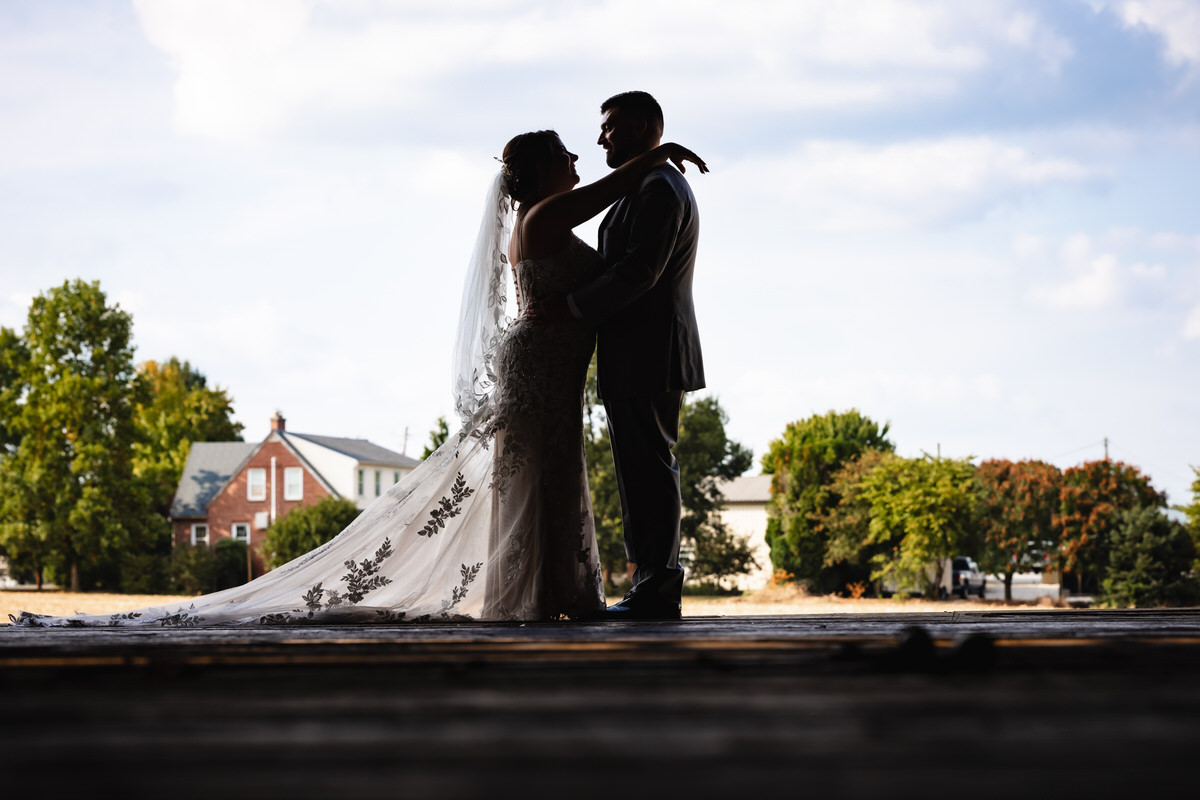 Silhouette of the married couple looking out of the barn during their family farm wedding.