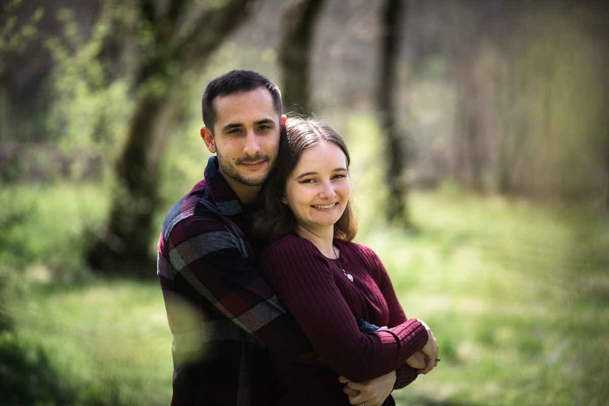 Guy's arms wrapped around his fiance in the woods at Lake Redman engagement