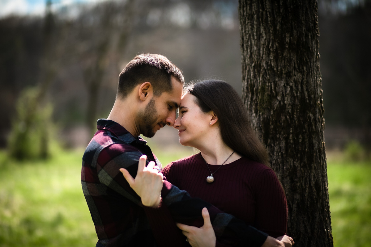 Girl grasping her fiance's arm in the lush wooded area of the forest