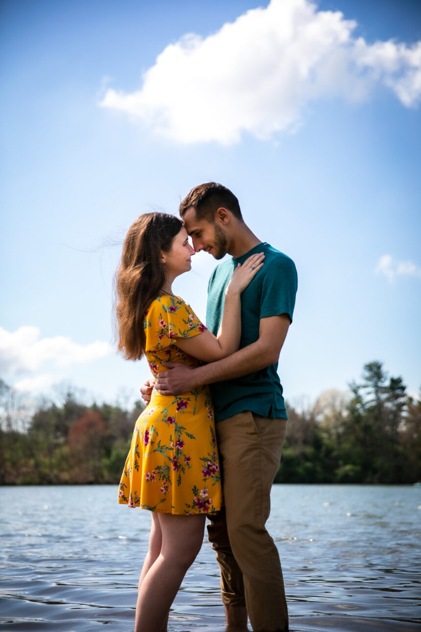 Couple leaning foreheads together and smiling while the stand in the lake