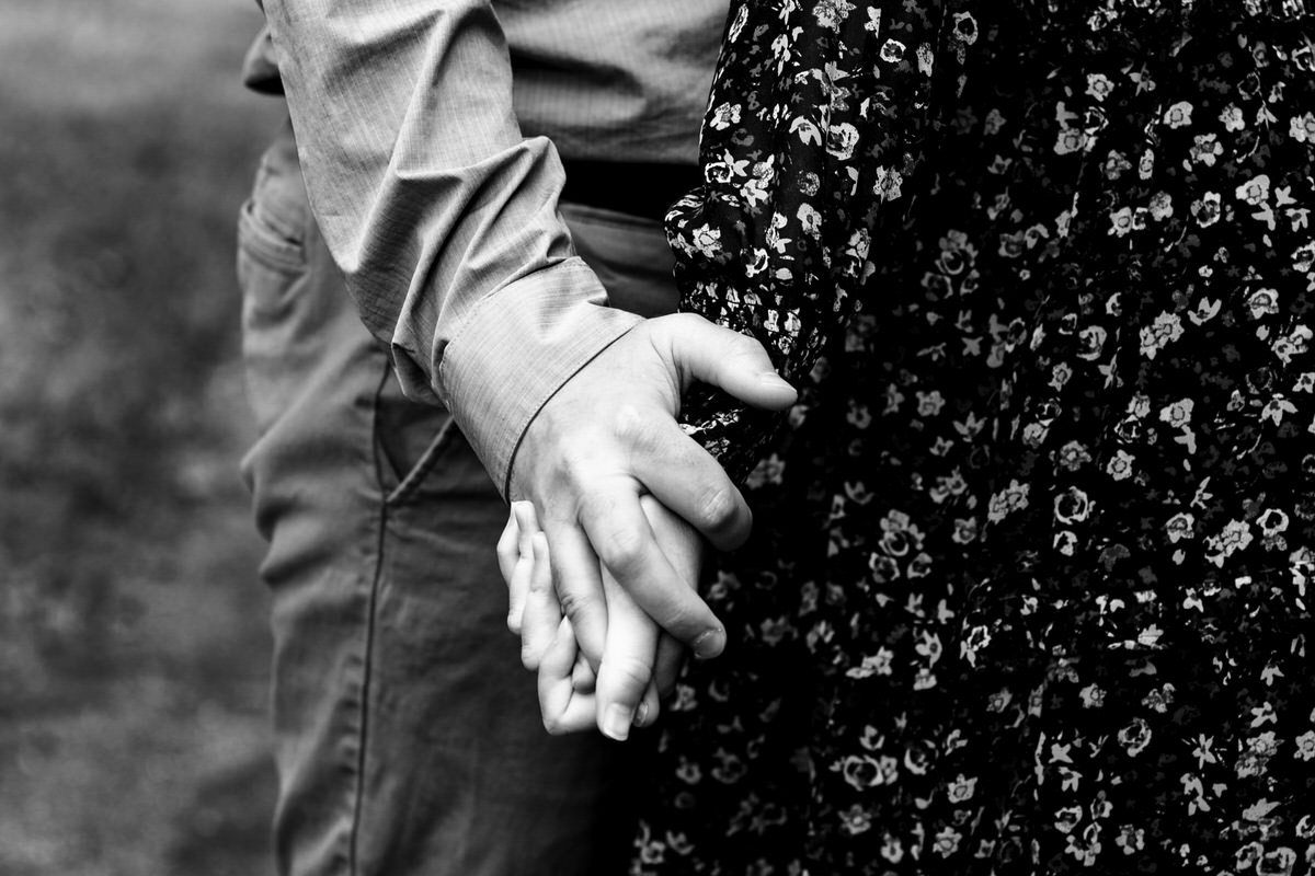 Close up black and white photo of Mariah and Chris holding hands.