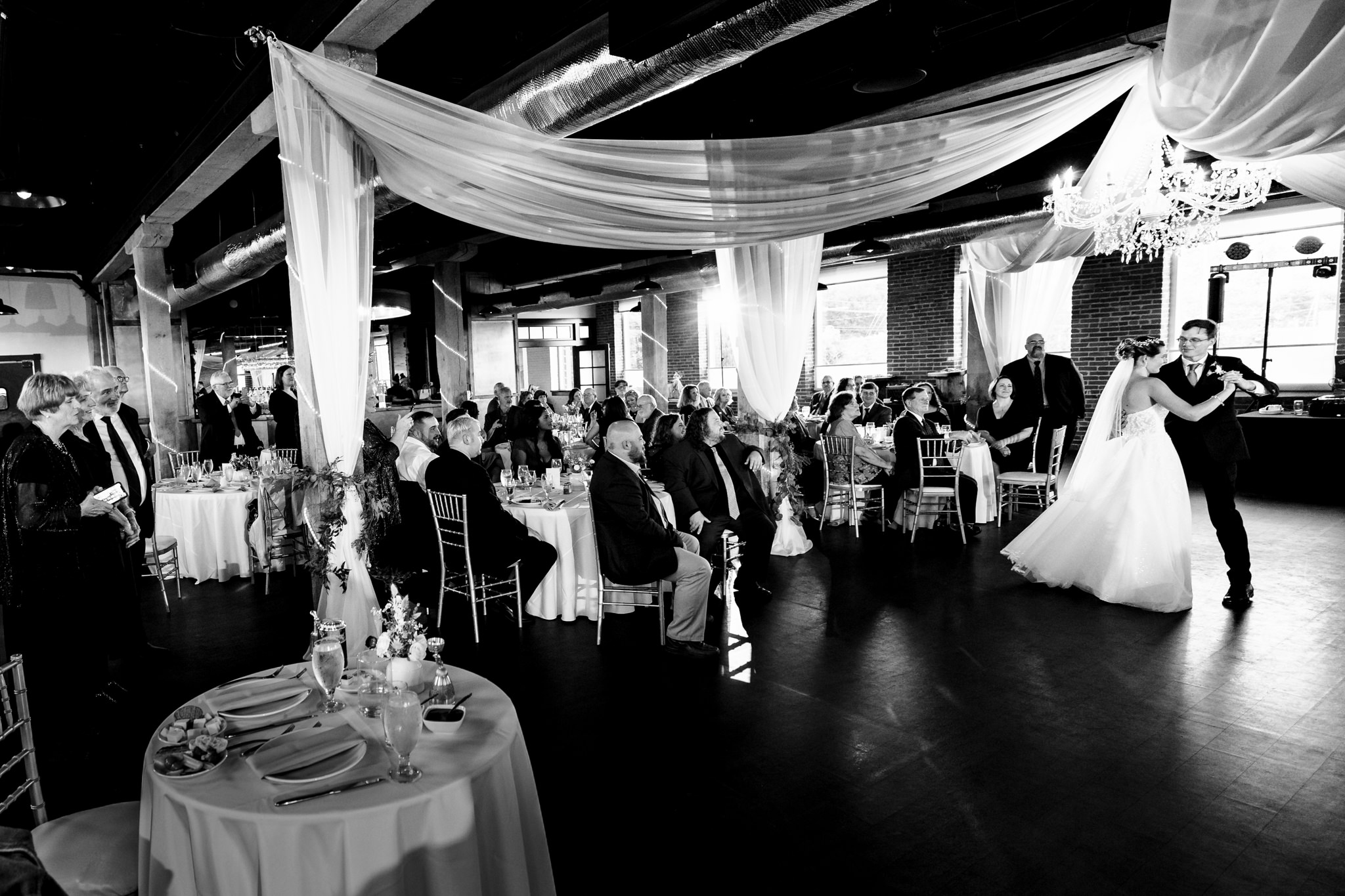 Family and friends watching couple enjoy their first dance at John Wright Wedding reception.