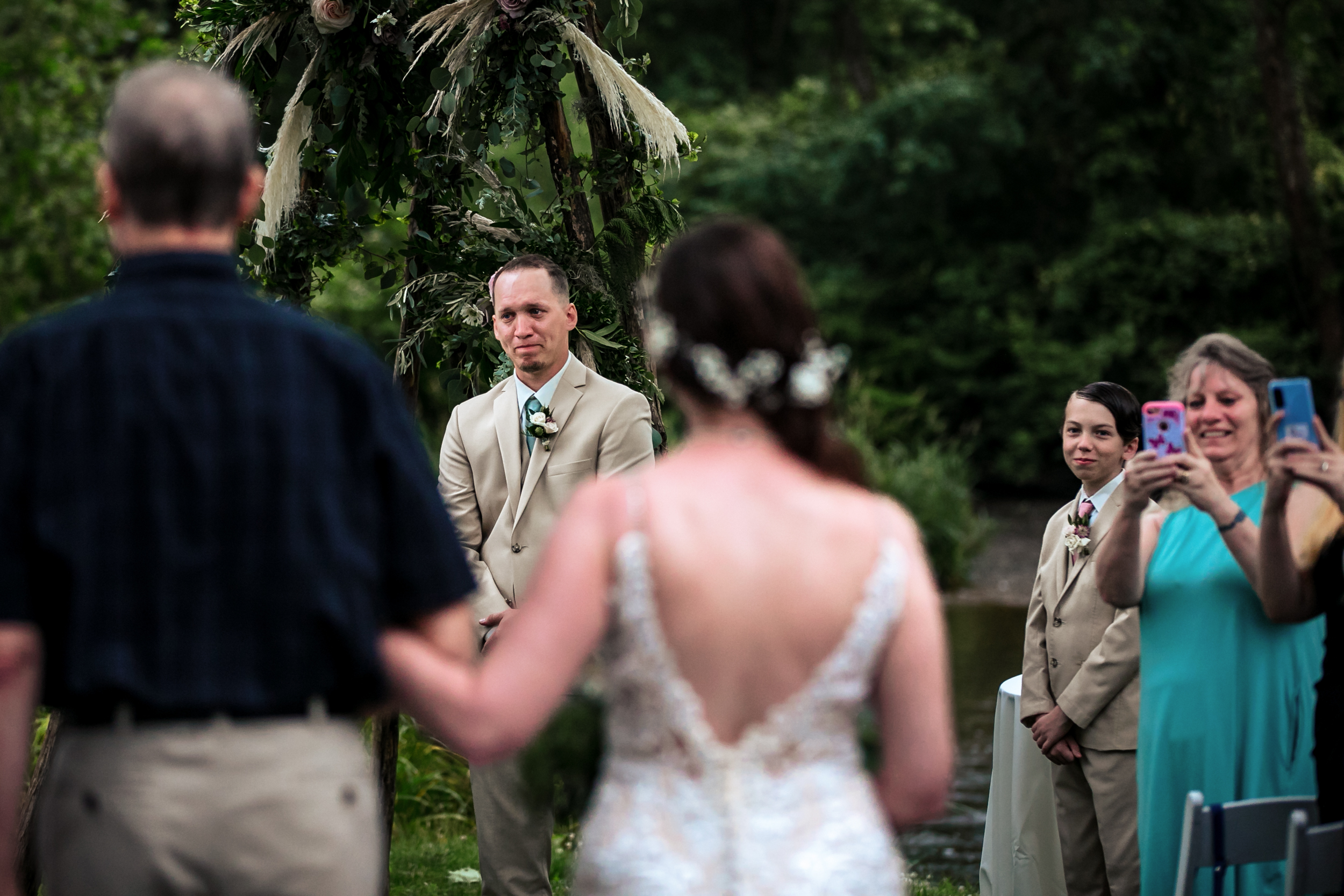 Lancaster Wedding Photographer documents husband tearing up as his bride walks down the aisle toward him.