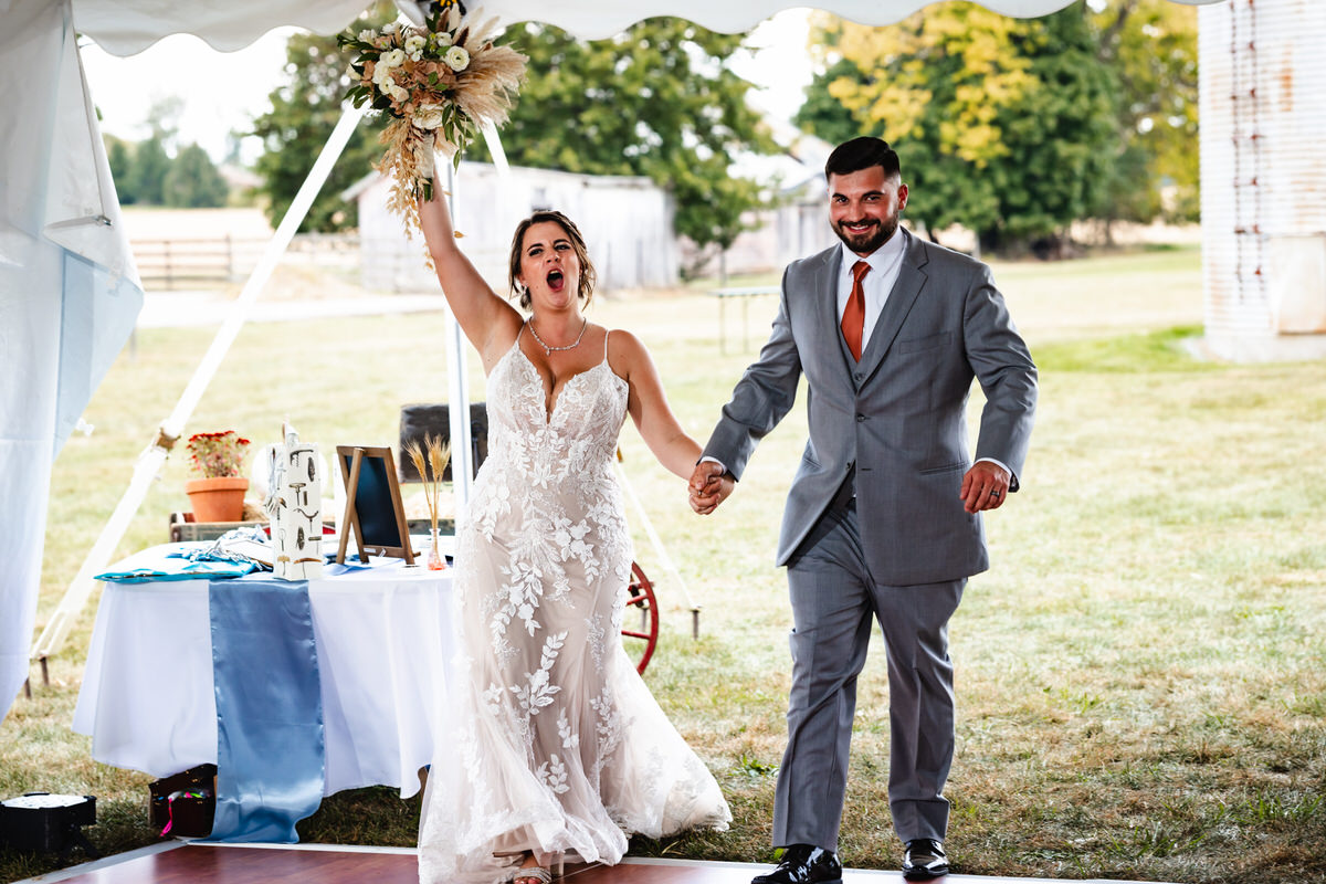 Candid moment of couple entering reception and cheering.